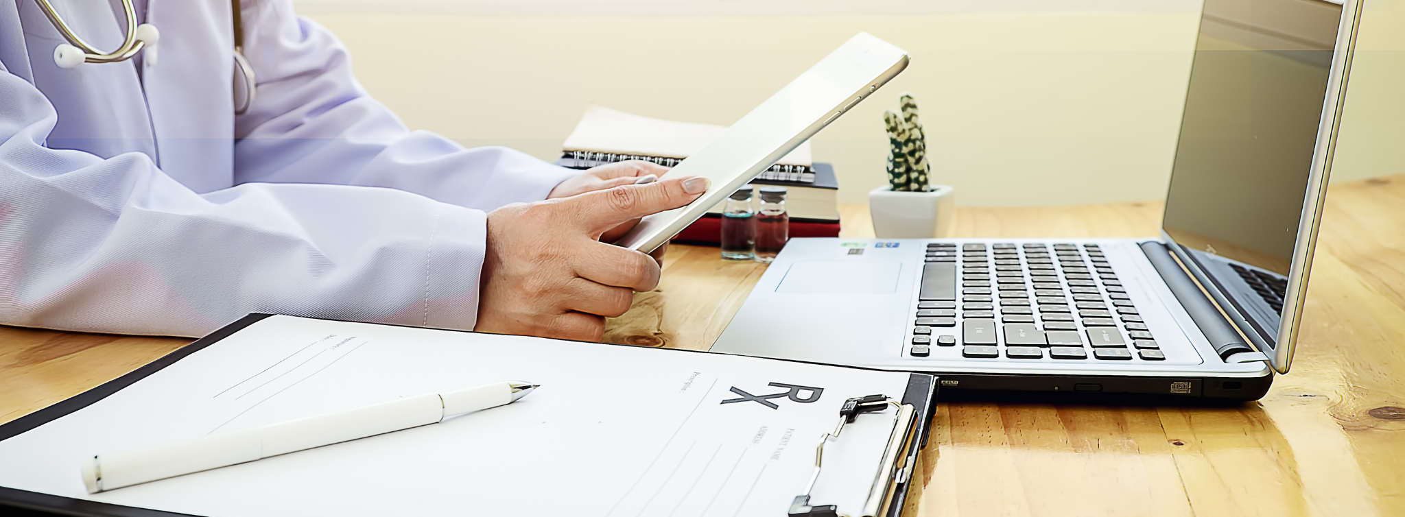 A medical professional or healthcare administrator reviewing medical billing files next to an open laptop computer.